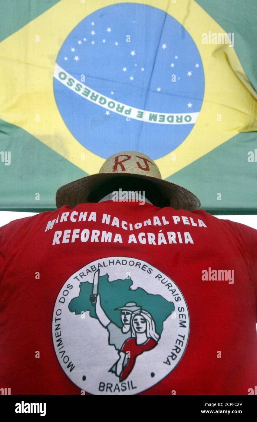 A member of Brazil's Landless Movement poses beneath the national flag atop Corcovado mountain in Rio de Janeiro, prior to launching a demand for large scale agrarian reform in the country, April 29, 2005. Brazil's rural workers will begin their 180 mile journey in the "National March for Land Reform" on May 1 from the city of Goiania in central Brazil and converge on the capital of Brasilia 30 days later. REUTERS/Bruno Domingos  SM/GN Stock Photo