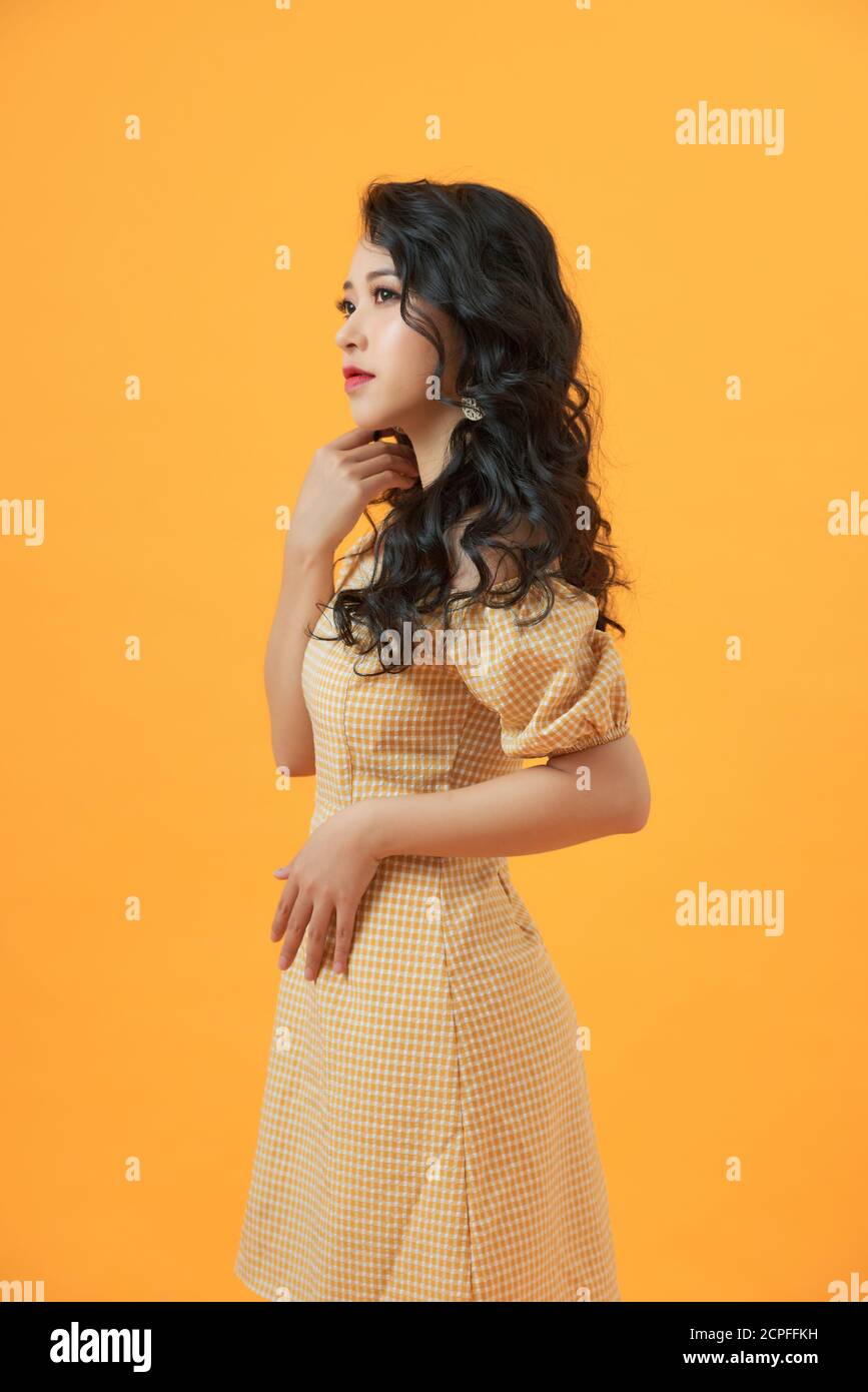 young beautiful confident girl in dress on yellow background Stock Photo