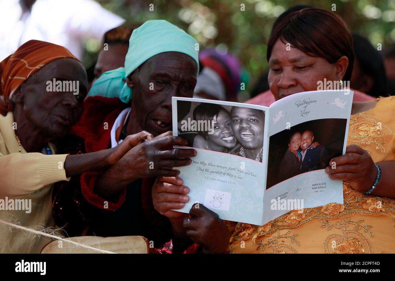 Villagers read the biography of Mbugua Maina and Maina's fiancee Rosemary Wahito, who were both killed during the Westgate Mall shopping mall attack, during their burial in Gatundu village near Nairobi, September 27, 2013. At least 72 people were killed in the attack which occurred over the weekend. REUTERS/Thomas Mukoya (KENYA - Tags: CIVIL UNREST CRIME LAW OBITUARY) Stock Photo