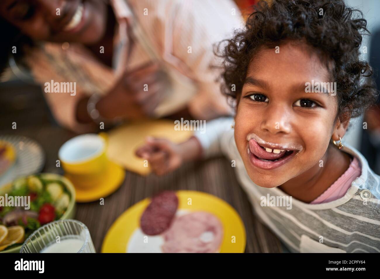 Cute female child licking her lips after tasty diner Stock Photo