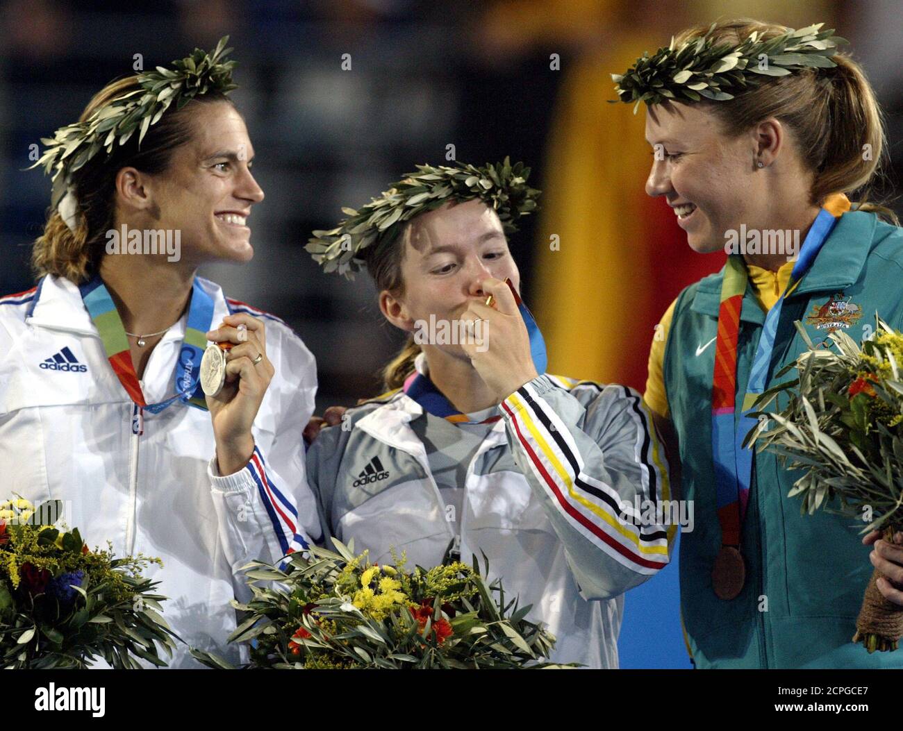 Gold medallist Henin-Hardenne kisses the medal while silver medallist Mauresmo and bronze medallist Molik watch after the ceremony for the women's single tennis event of Athens 2004 Olympic Games.  Gold medallist Belgium's Justine Henin-Hardenne (C) kisses the medal while silver medallist France's Amelie Mauresmo (L) and bronze medallist Australia's Alicia Molik (R) watch after the ceremony for the women's single tennis event of Athens 2004 Olympic Games August 21, 2004. REUTERS/Carlos Barria Stock Photo