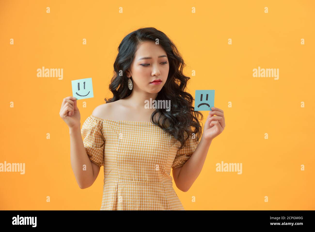 Photo of gloomy lady holding paper emoticons good and bad mood prefer negative emotions awful day Stock Photo
