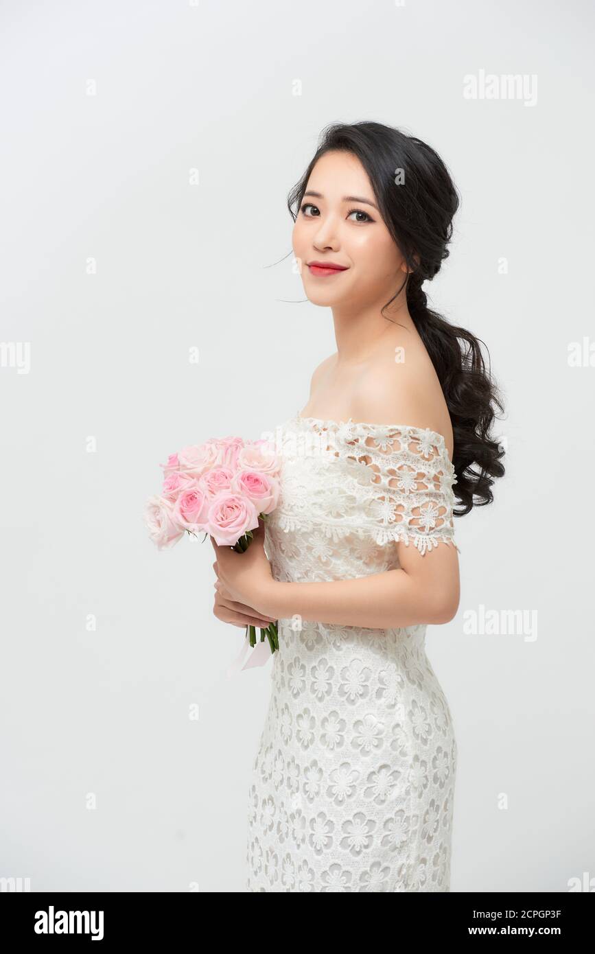 Young beautiful woman in a white dress posing with a bouquet of roses ...
