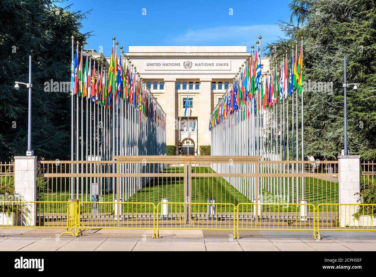 Front view of the avenue of flags and facade of the Palace of Nations, home of the United Nations Office at Geneva, Switzerland, on a sunny summer day Stock Photo