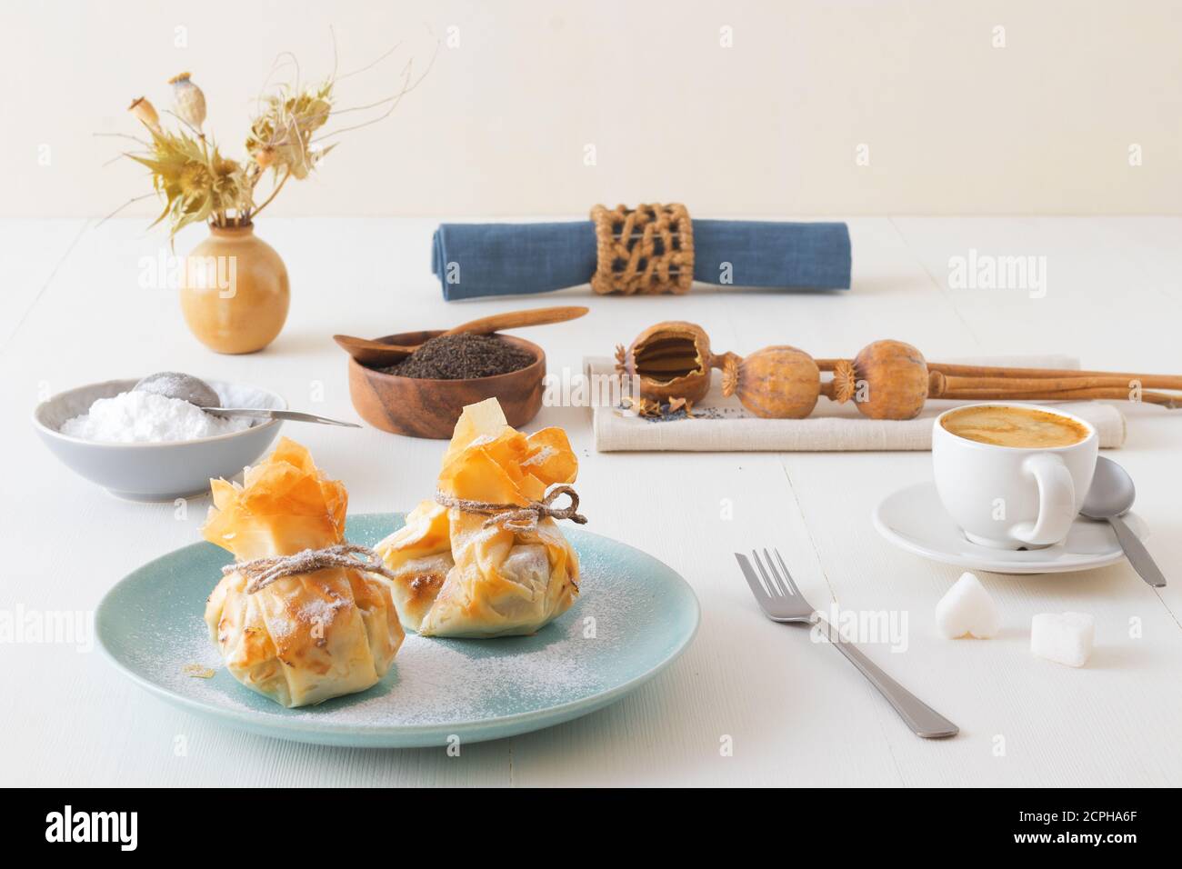 Plum and poppy seeds phyllo purses on a white wooden, delicious vegetarian dessert on a white wooden table. Stock Photo