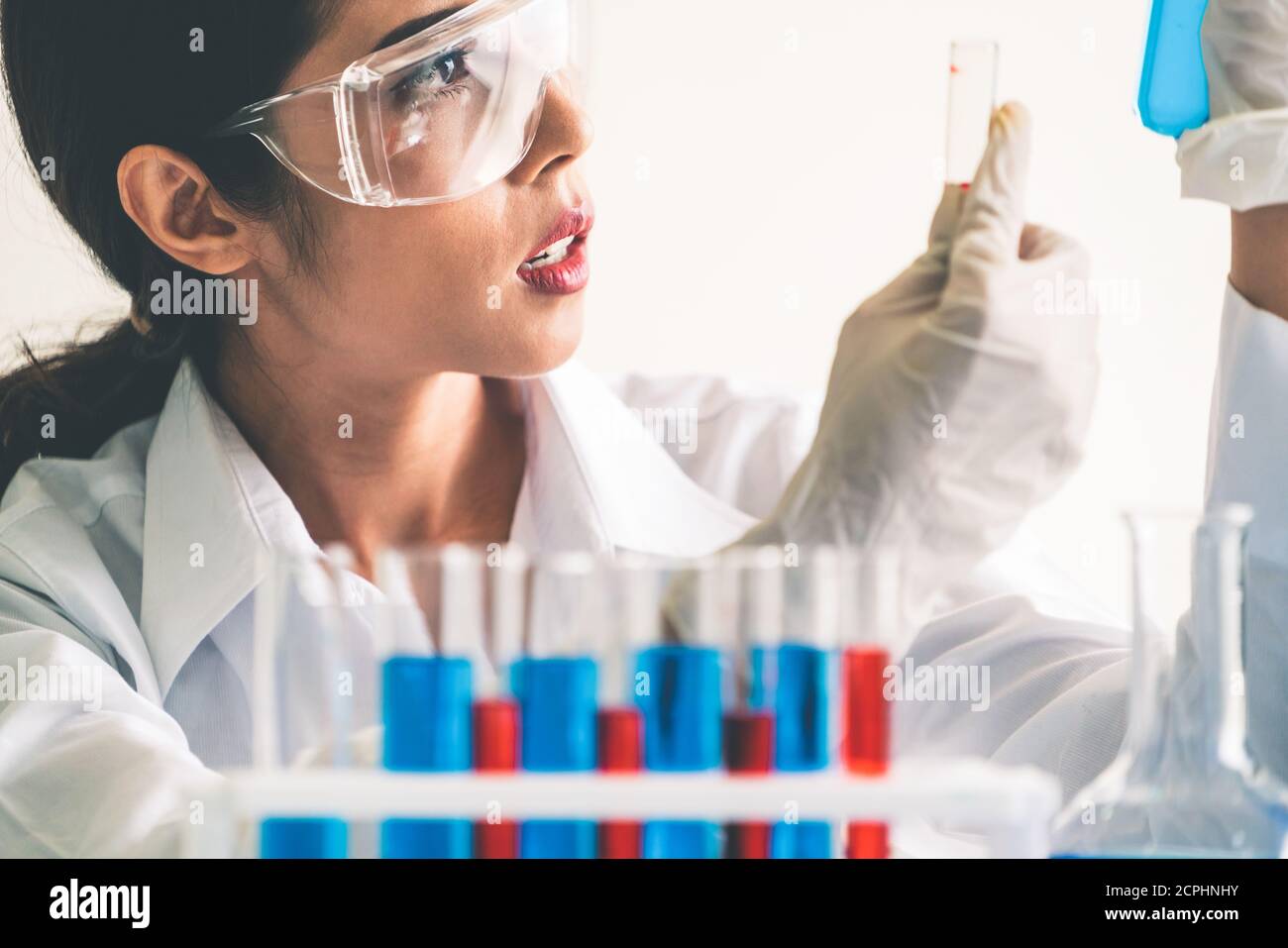 Woman scientist working in laboratory and examining biochemistry sample in test tube. Science technology research and development study concept. Stock Photo