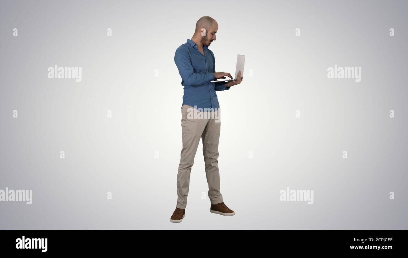 Young middle eastern businessman, standing and typing on laptop Stock Photo