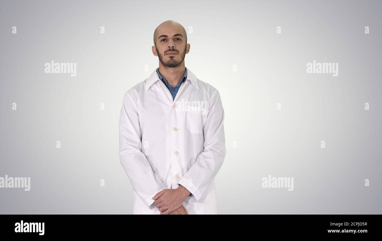 Standing young serious arab doctor on gradient background. Stock Photo