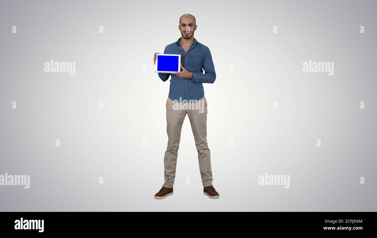 Smiling casual man presenting a tablet with a blank screen on gr Stock Photo