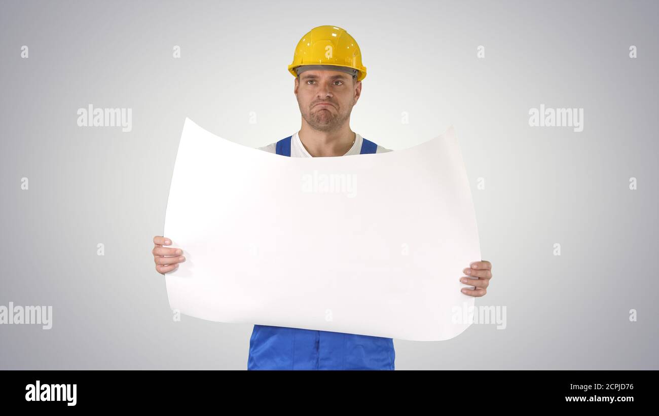 Construction worker checking blueprints on site on gradient back Stock Photo