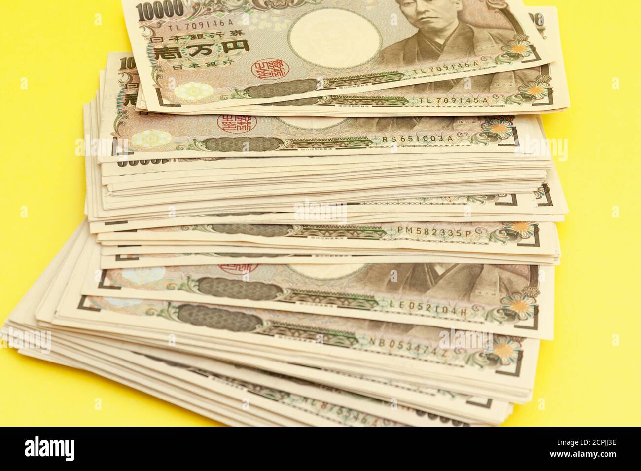 Ten thousand yen (10,000 yen) banknotes stacked. Japanese money. Paper money. Isolated on yellow background. Top view. Close-up. Stock Photo