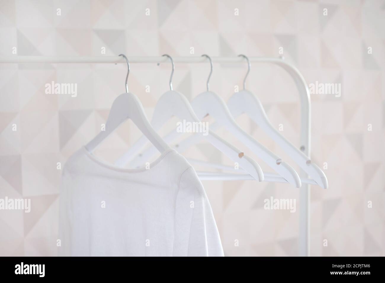 White cotton T-shirt hanging on a white wooden hanger Stock Photo