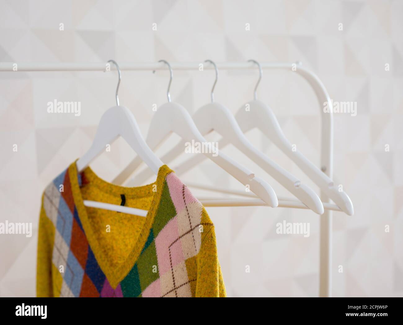 Knitted cardigan weighs on a white clothes hanger Stock Photo