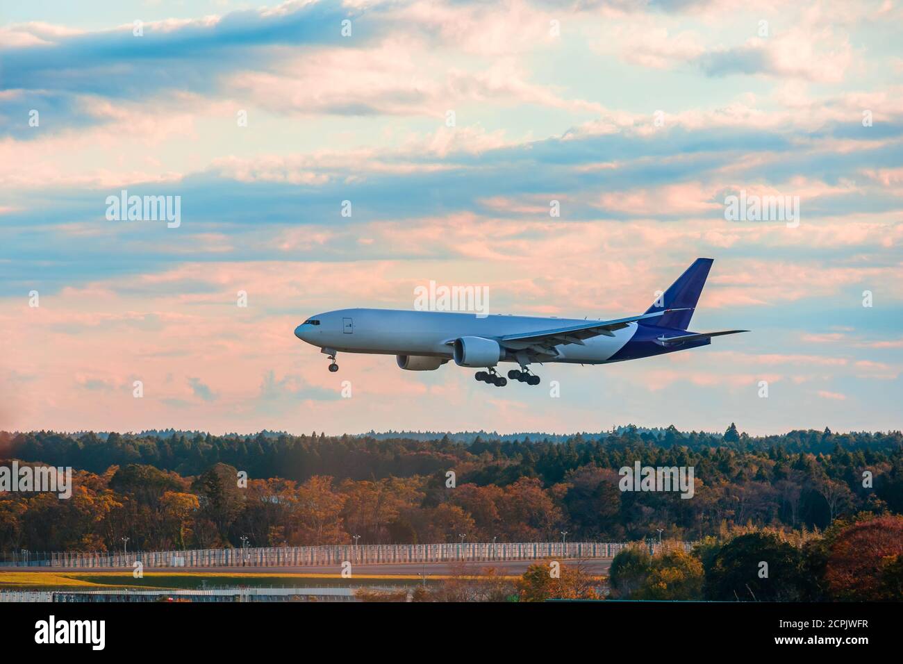 Landing airplane in the morning.Landscape with front of big airplane is flying over runway and trees in autumn.Travel background. Passenger plane. Com Stock Photo