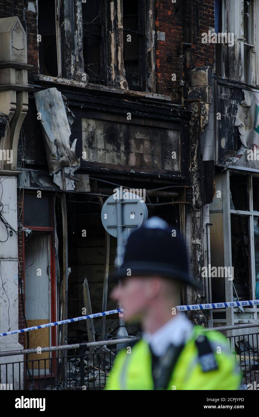Police guard the smashed and burnt out shops and buildings after London riots Stock Photo