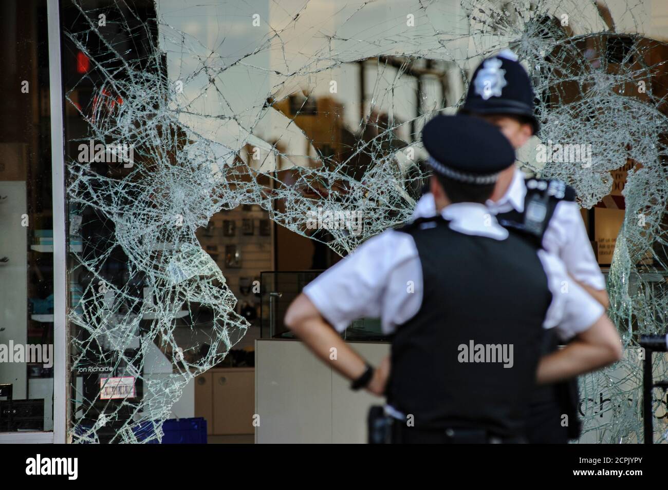 Police guard the smashed and burnt out shops and buildings after London riots Stock Photo