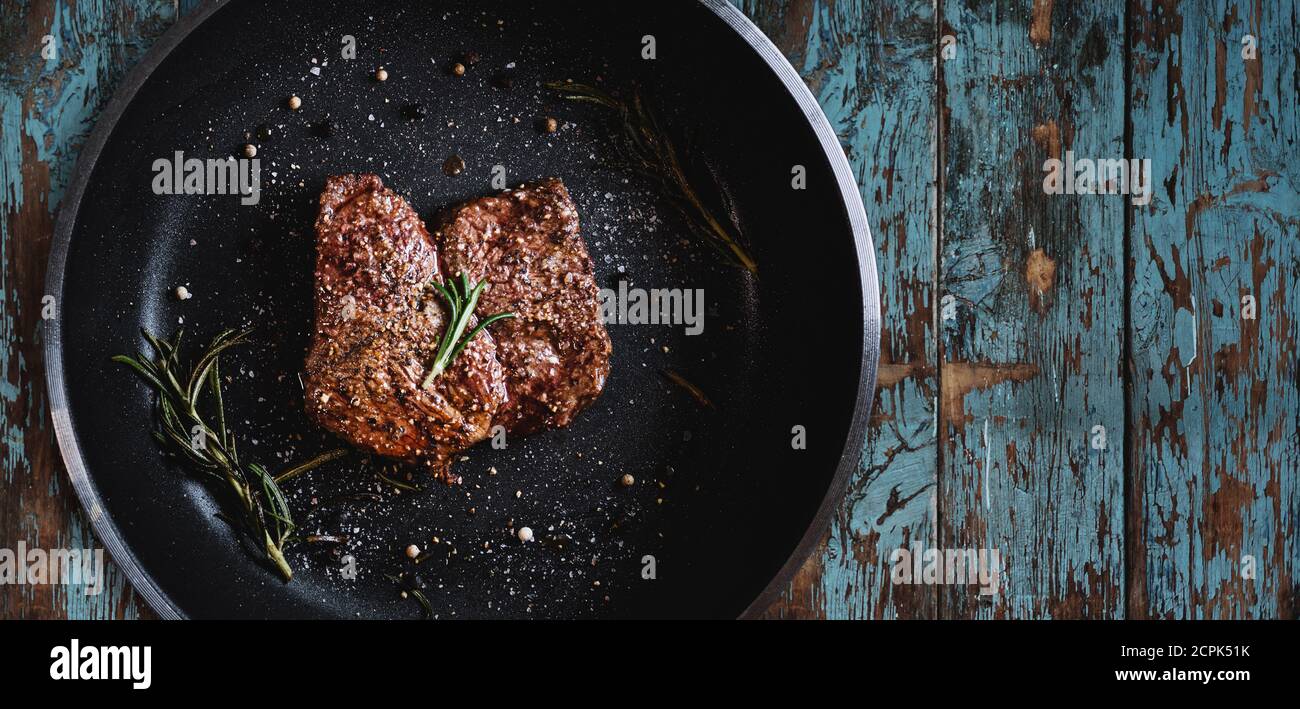 Grilled beef steak in frying pan, on wood texture Stock Photo
