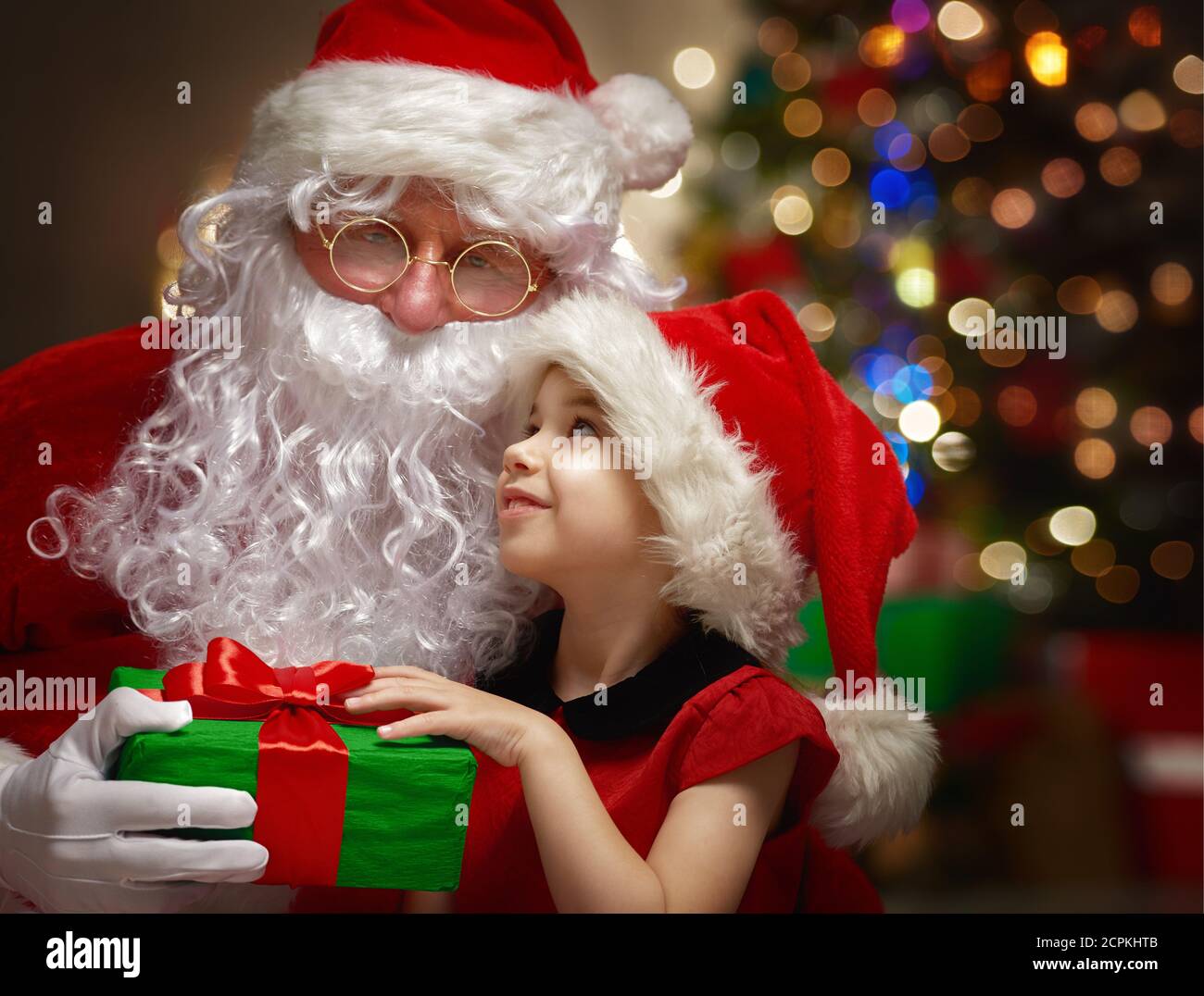 Santa Claus giving a present to a little cute girl Stock Photo - Alamy