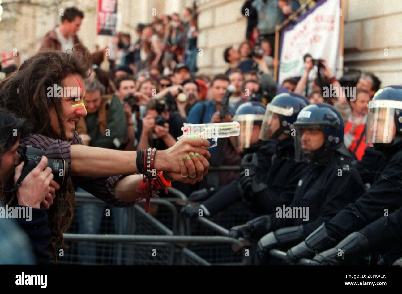 An environmental protester points a water pistol at London policemen forming a line at the gates of Prime Minister John Major's Downing Street residence April 12. Police later charged at the marchers on horseback after bottles and a smoke grenade were thrown.  BRITAIN MARCH Stock Photo