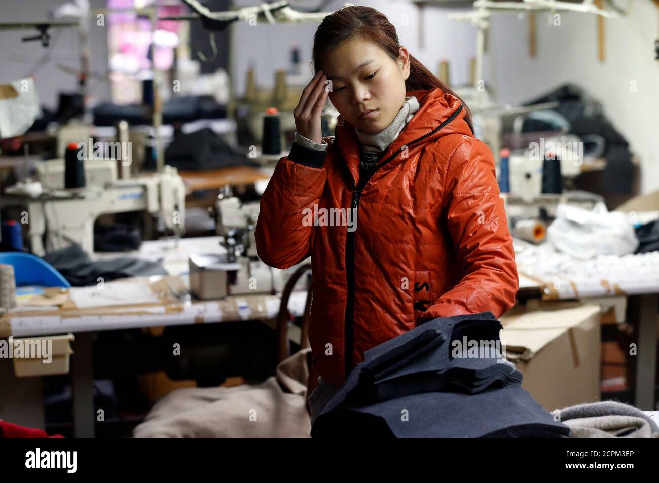 A Chinese immigrant gestures as police officers conduct a check at the Shen Wu textile factory in Prato December 9, 2013. Prato, the historical capital of Italy's textile business, has attracted the largest concentration of Chinese-run industry in Europe within less than 20 years. Yet Prato is also a thriving hub of illegality committed by both Italians and Chinese, a byproduct of globalisation gone wrong, many people in the city say. Picture taken December 9, 2013. To match Insight ITALY-SWEATSHOP/ REUTERS/Stefano Rellandini  (ITALY - Tags: BUSINESS TEXTILE SOCIETY IMMIGRATION) Stock Photo