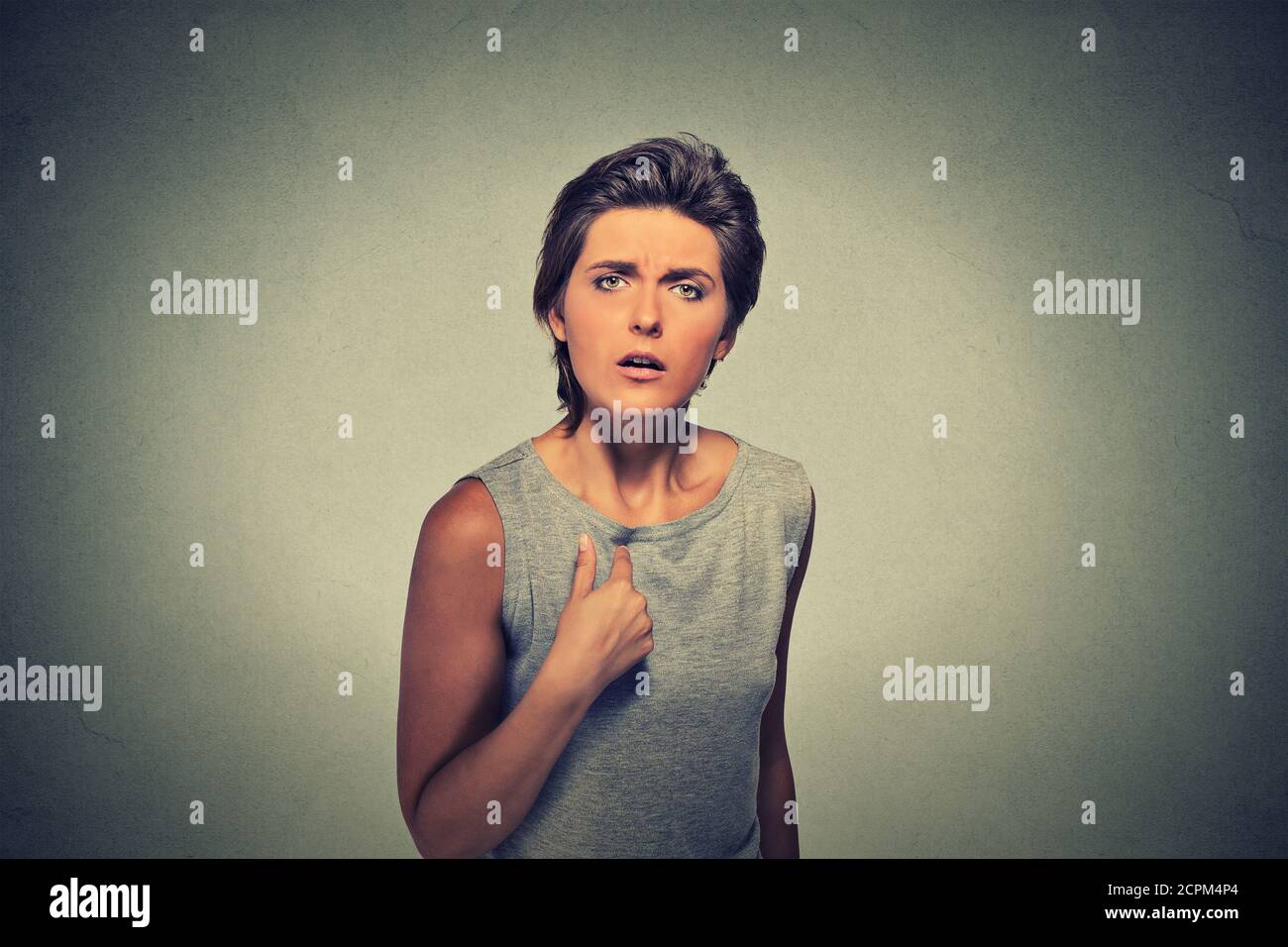 Portrait angry, unhappy, annoyed young woman, getting mad asking question you talking to me, you mean me? Isolated on gray wall background. Negative e Stock Photo
