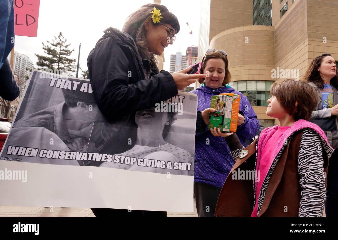 Girl Scout Lucy Bassett (R) sells boxes of Girl Scout cookies to a Planned Parenthood supporter at a protest in downtown Denver, U.S., February 11, 2017. The top of the sign reads, 'That awkward moment'.  REUTERS/Rick Wilking Stock Photo