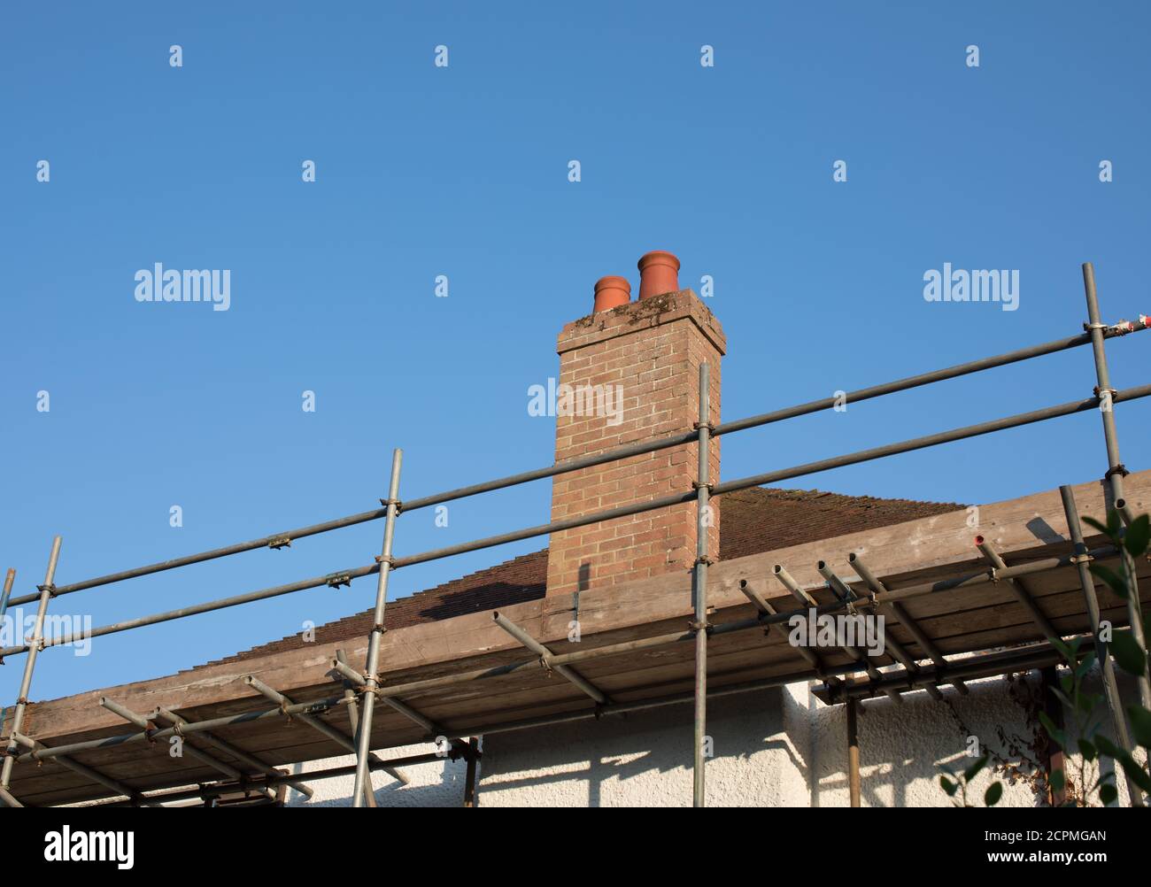 Scaffolding attached to a 1920s house preparatory to removing the clay tiles and re-roofing. Stock Photo