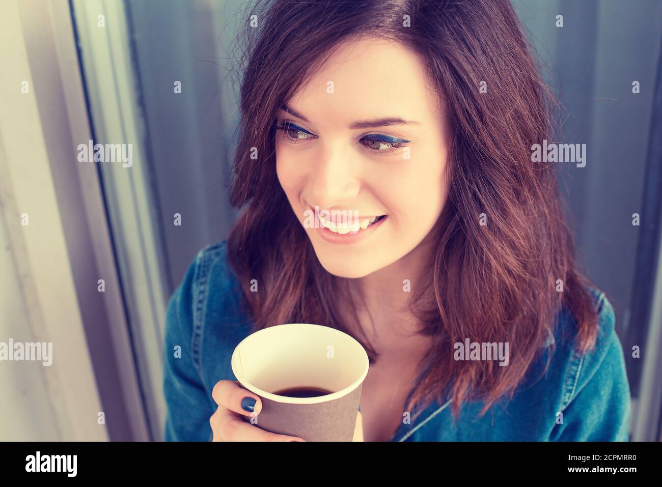 Smiling woman drinking coffee outdoors holding paper cup Stock Photo