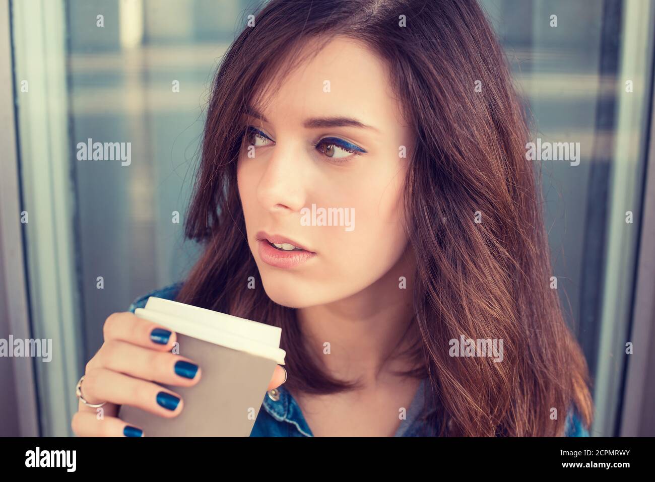 Portrait of a young woman drinking coffee outdoors holding paper cup Stock Photo
