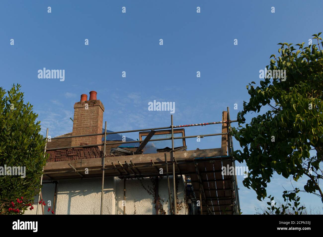 Scaffolding attached to a 1920s house preparatory to removing the clay tiles and re-roofing. Stock Photo