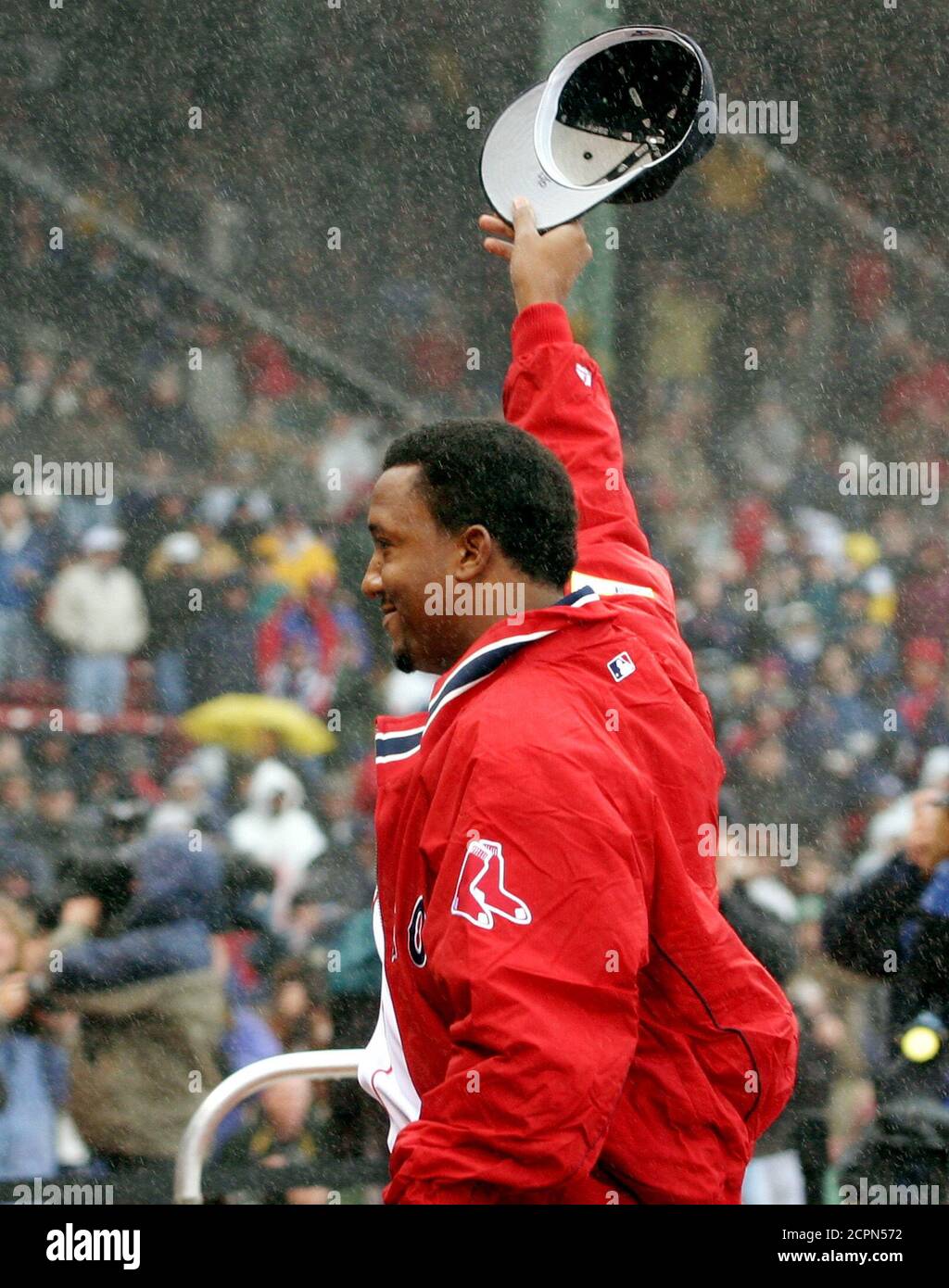 Three-time Cy Young award winning pitcher Pedro Marinez waves to Boston Red Sox fans at Fenway Park as he stands in the pouring rain during ceremonies before the Red Sox scheduled home opener April 11, 2003 in Boston. The game between the Boston Red Sox and the Baltimore Orioles was called off and delayed until another day due to the heavy rain. REUTERS/Jim Bourg  JRB Stock Photo