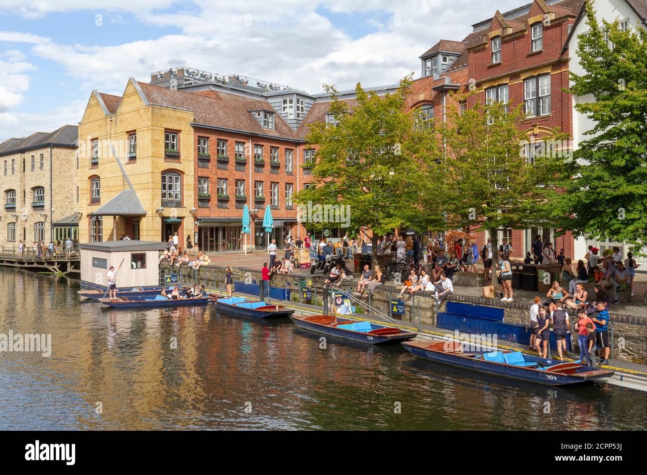 People enjoying a summer afternoon beside punts on the River Cam viewed from Magdalene Bridge, Cambridge, UK. Stock Photo