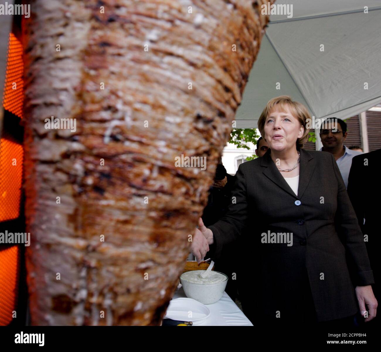 German Chancellor Angela Merkel looks at a kebab meat loaf at a reception of the medium-sized business parliamentary group (PKM) in Berlin, June 30, 2009.  REUTERS/Thomas Peter  (GERMANY POLITICS FOOD BUSINESS) Stock Photo