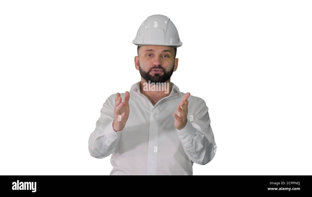 Engineer in a white helmet explaining something to camera on whi Stock Photo