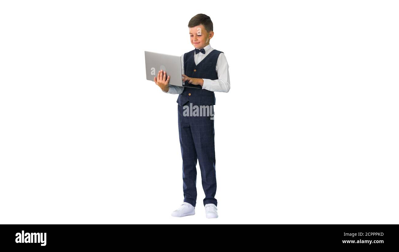 Smiling boy in a bow tie and waistcoat using laptop computer whi Stock Photo