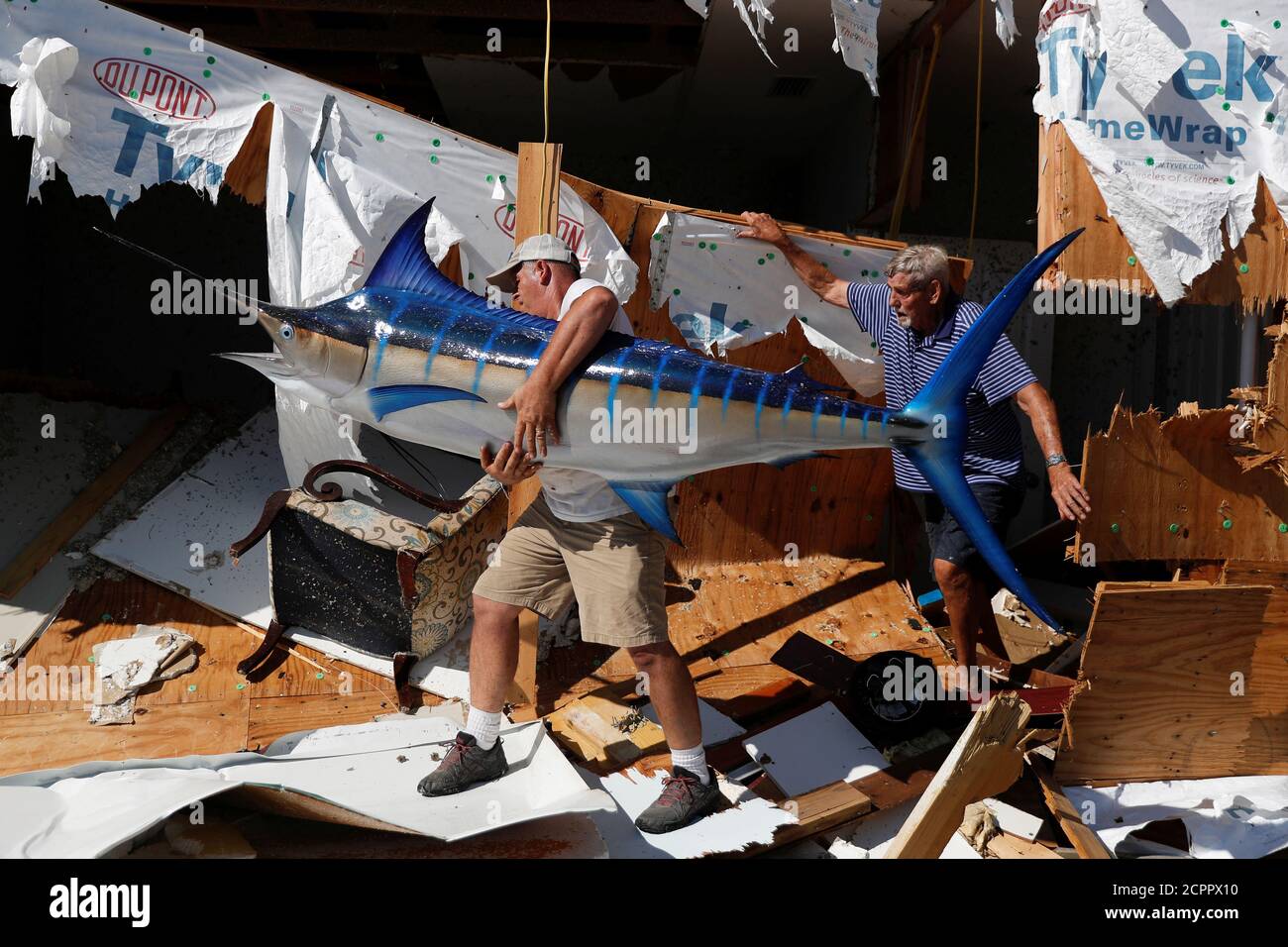 Mark Drake, 55, of Tallahassee, (L) helps Charles Anderson, 76, of  Thomasville, GA, remove a stuffed blue marlin from Anderson's vacation home  damaged by Hurricane Michael in Mexico Beach, Florida, U.S., October