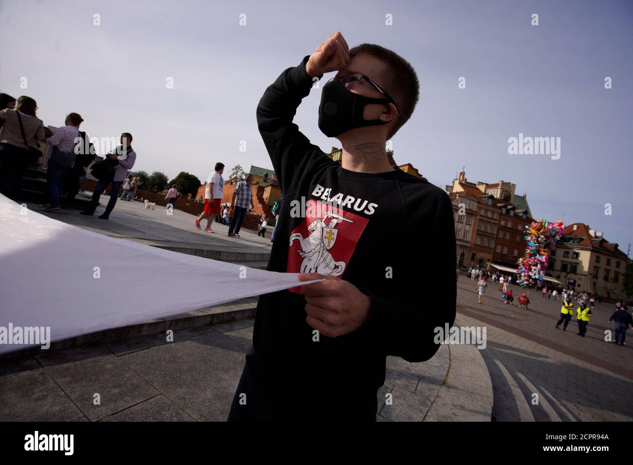 A man with a Pogon symbol on his sweater holds a large, Belarusian White-Red-White flag in Warsaw, Poland on September 19, 2020. Several dozen people, Stock Photo