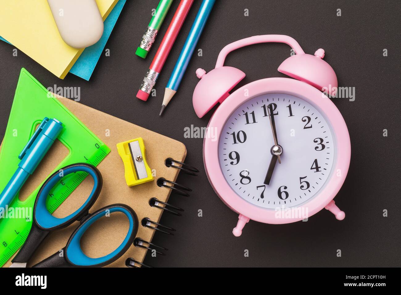 Alarm clock and school supplies on a black chalkboard. Concept do not