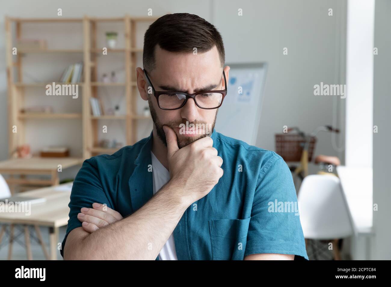 Thoughtful young businessman wearing glasses thinking about problem solution Stock Photo