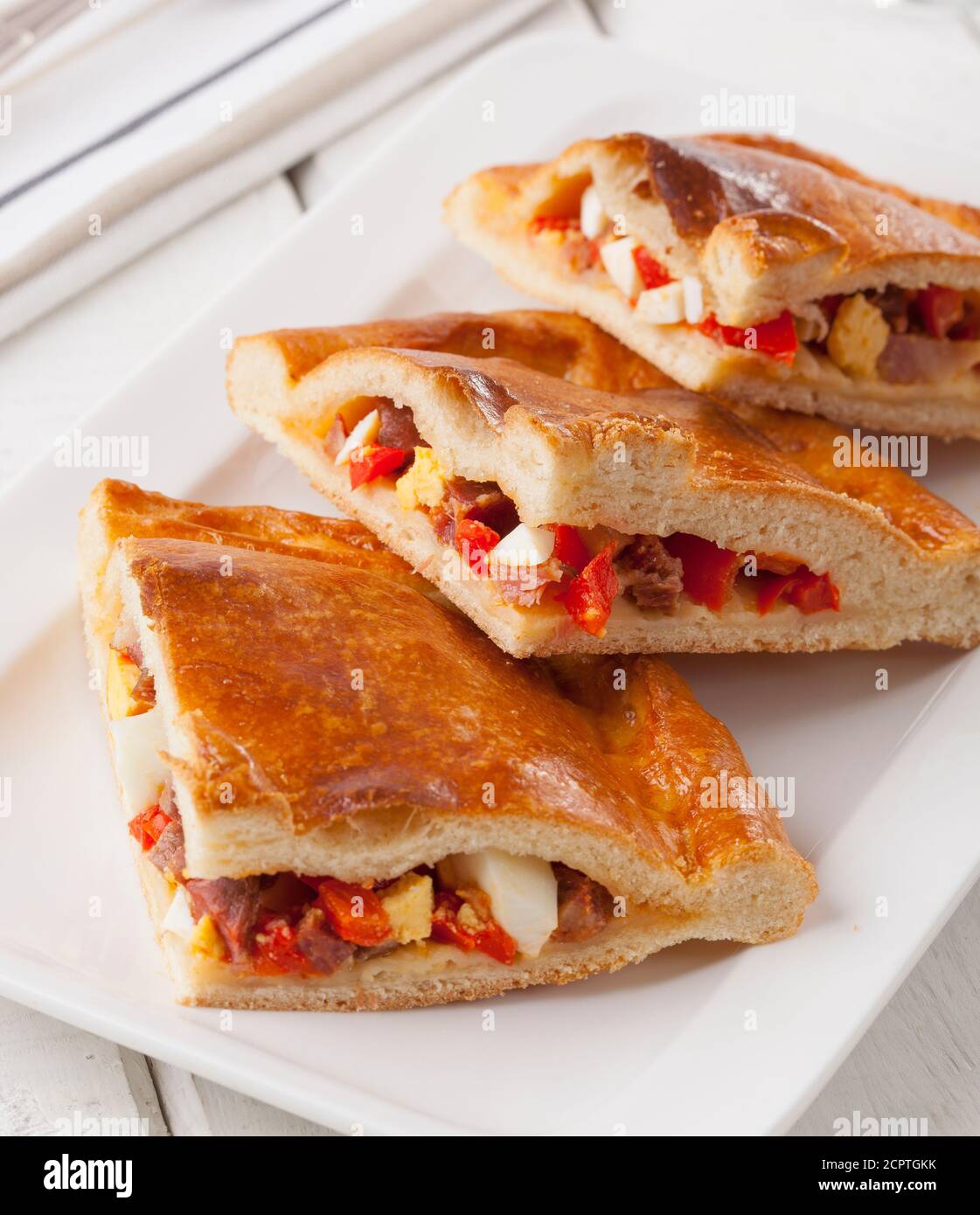 Spanish meat pie stuffed with Serrano ham, egg and bell pepper. Stock Photo