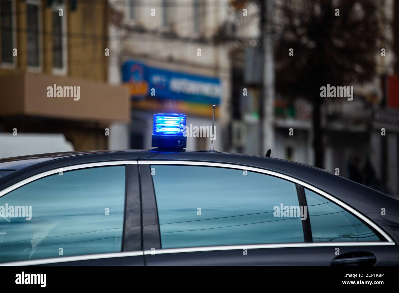 blue flashing light on top of black government car on daytime city