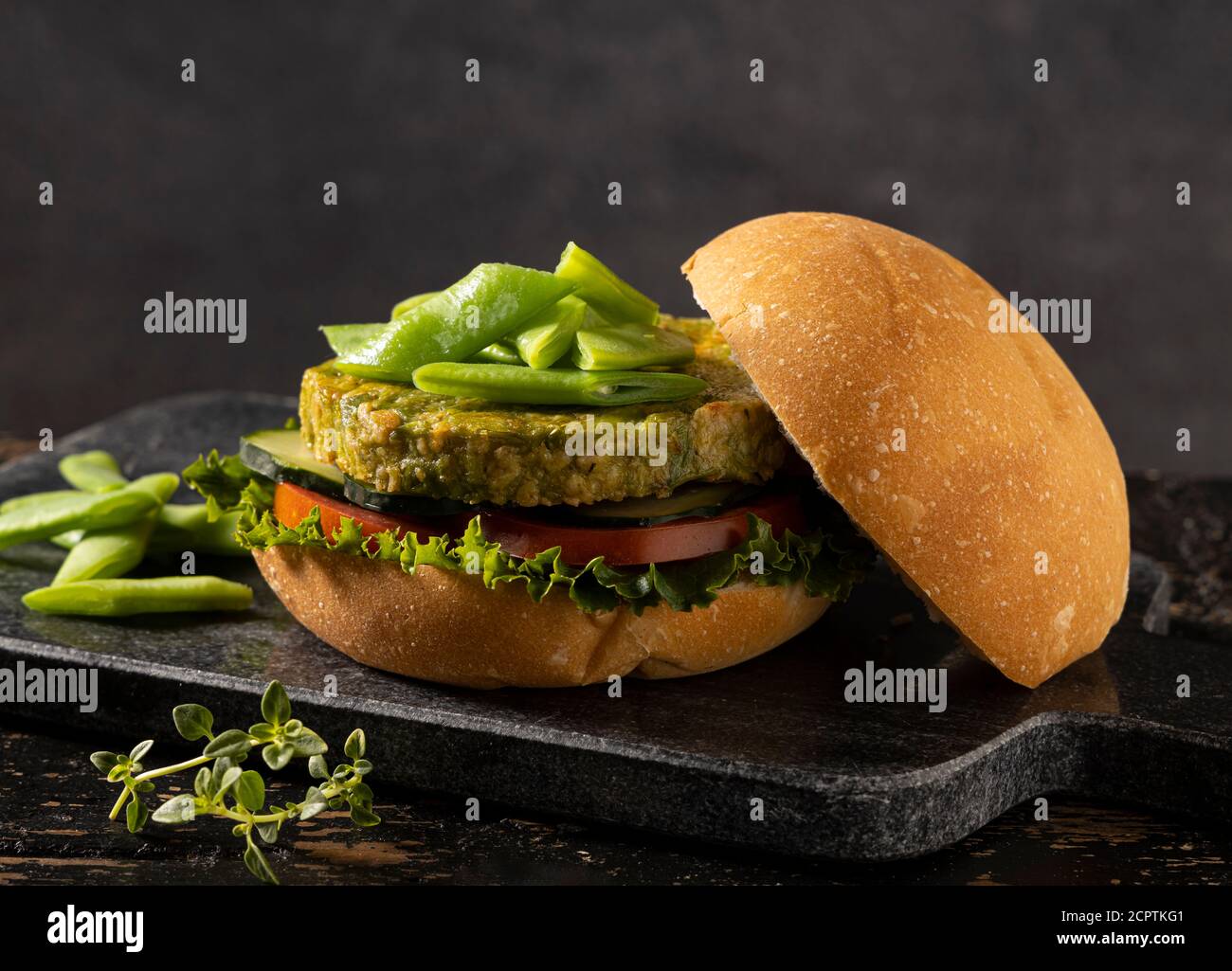 Vegan hamburger made with green beans and chickpeas, served with tomato, cucumber and lettuce. Stock Photo