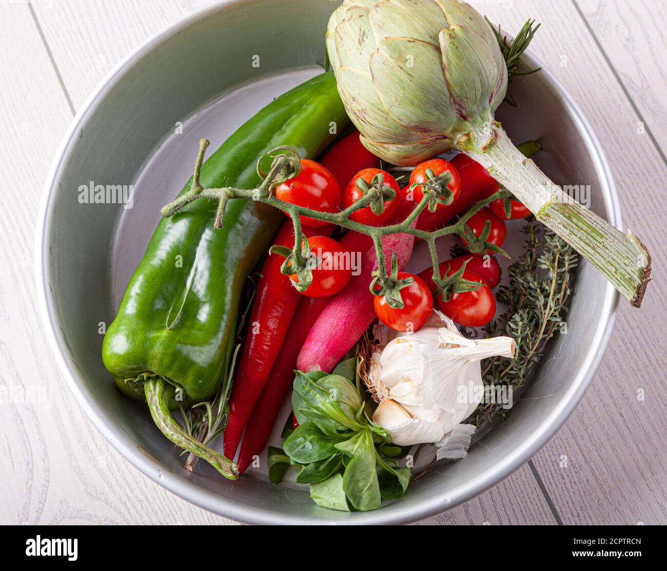 Fresh Italian vegetables and herbs: rosemary, oregano, artichoke, tomato, bell pepper, garlic, lamb lettuce and radish. Stock Photo