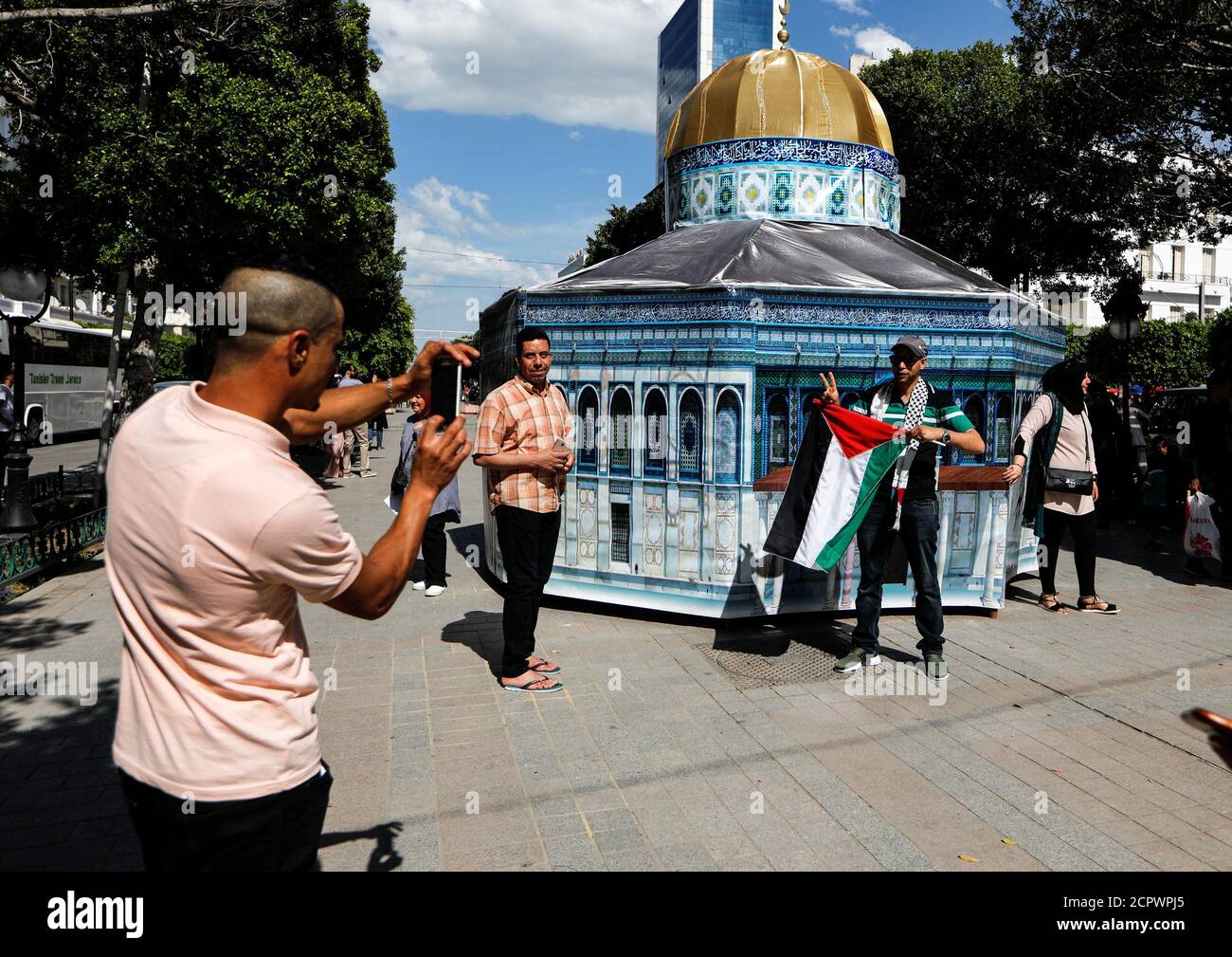 A man photographs his friends as they pose in front of a copy of Al Aqsa mosque, installed  as a protest against the killings of Palestinian protesters on the Gaza-Israel border and the U.S. embassy move to Jerusalem, in Tunis, Tunisia 15, 2018. REUTERS/Zohra Bensemra Stock Photo