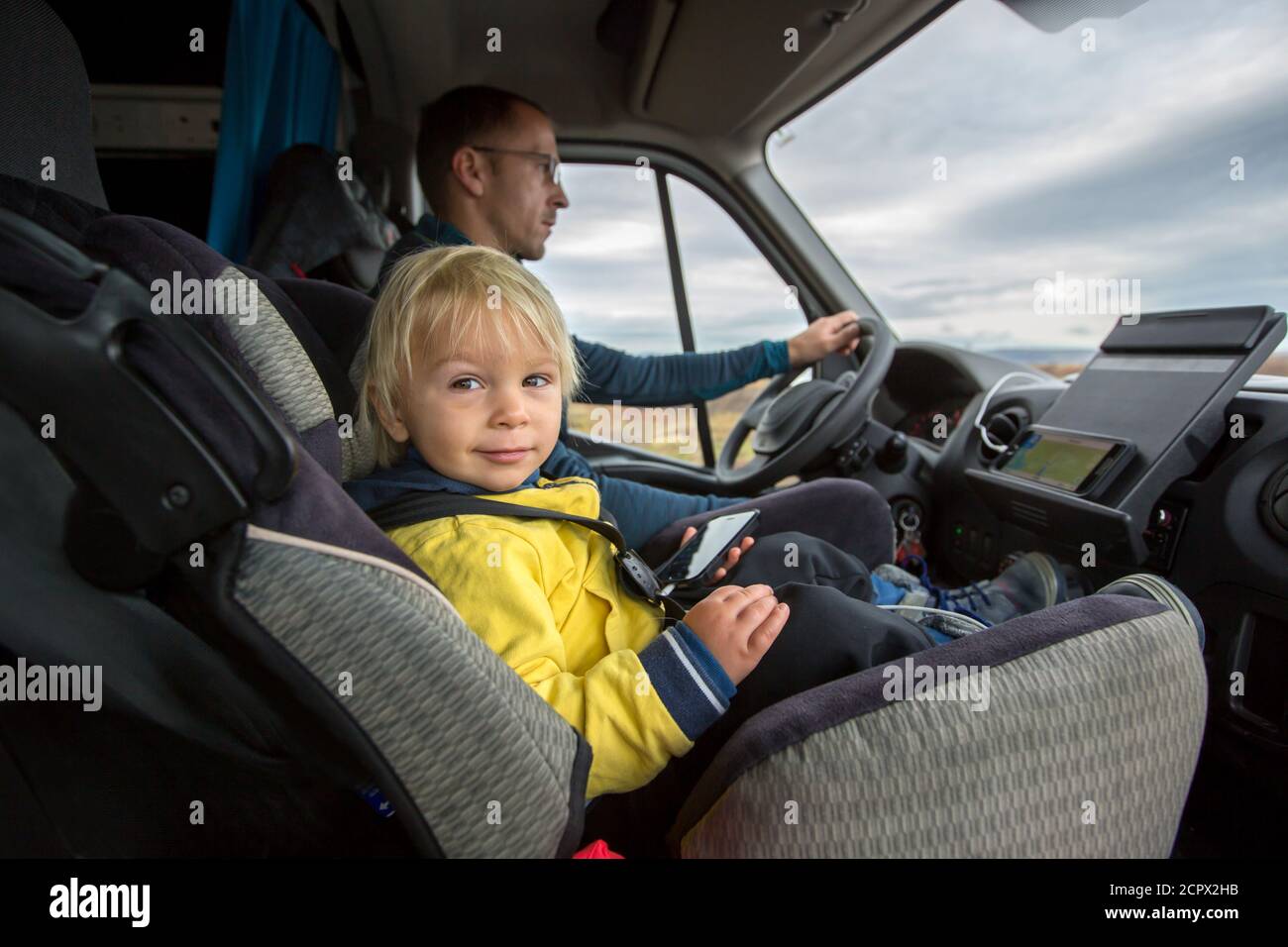 Cute toddler boy kid sitting on the front seat in child seat on