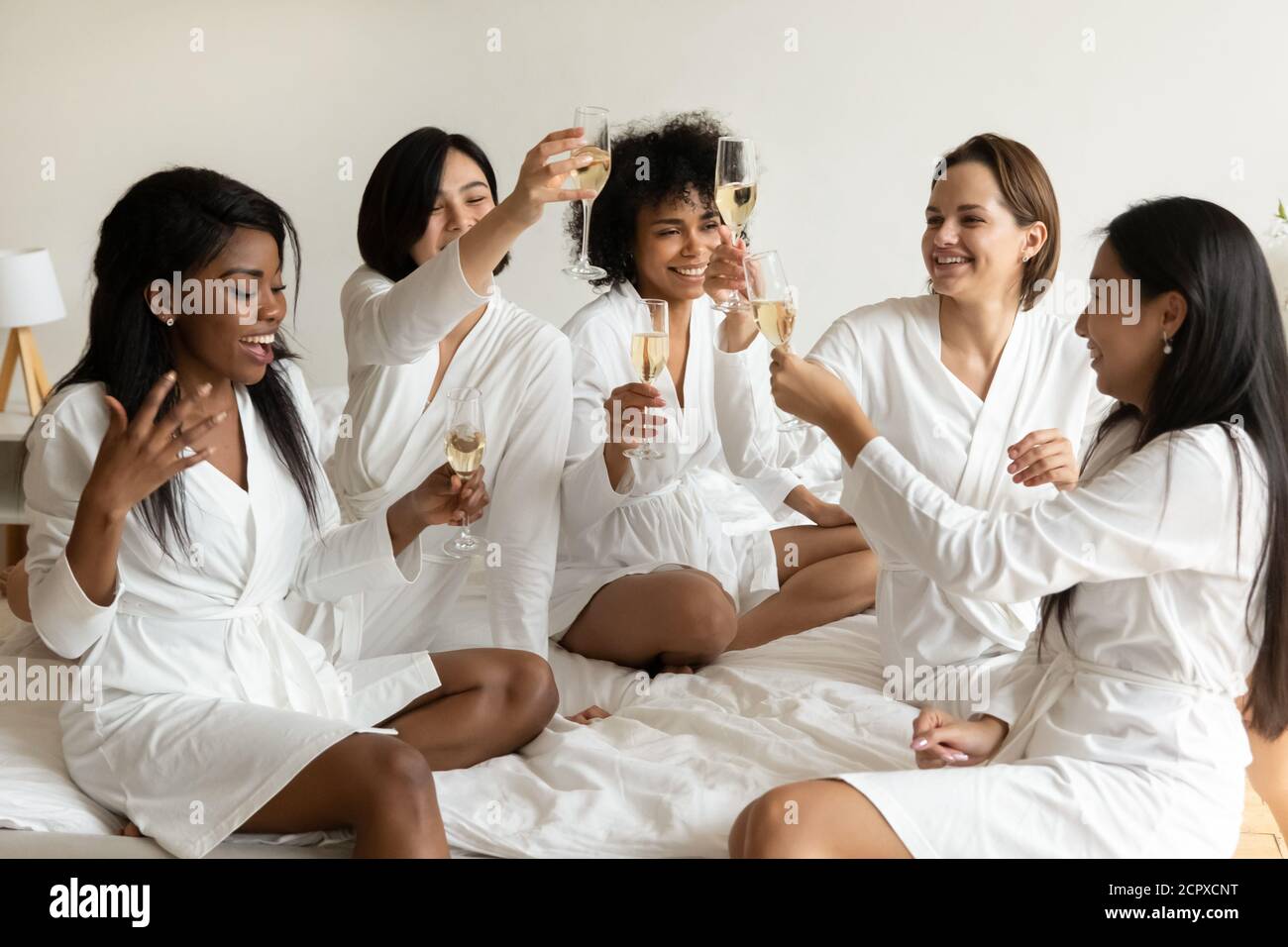 Happy young mixed race girlfriends celebrating birthday party. Stock Photo