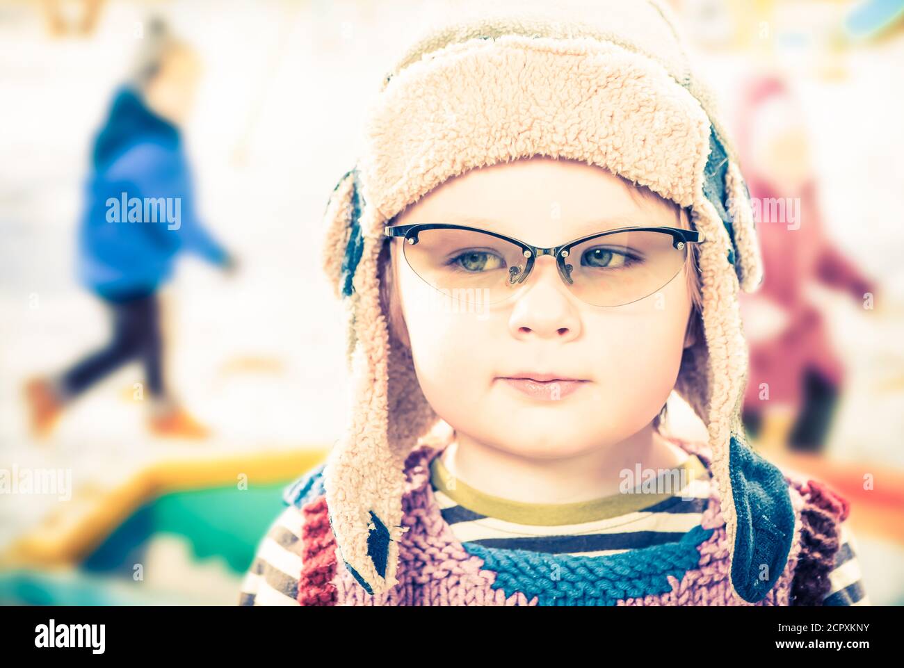 little boy portrait in hat and glasses with kids on background having
