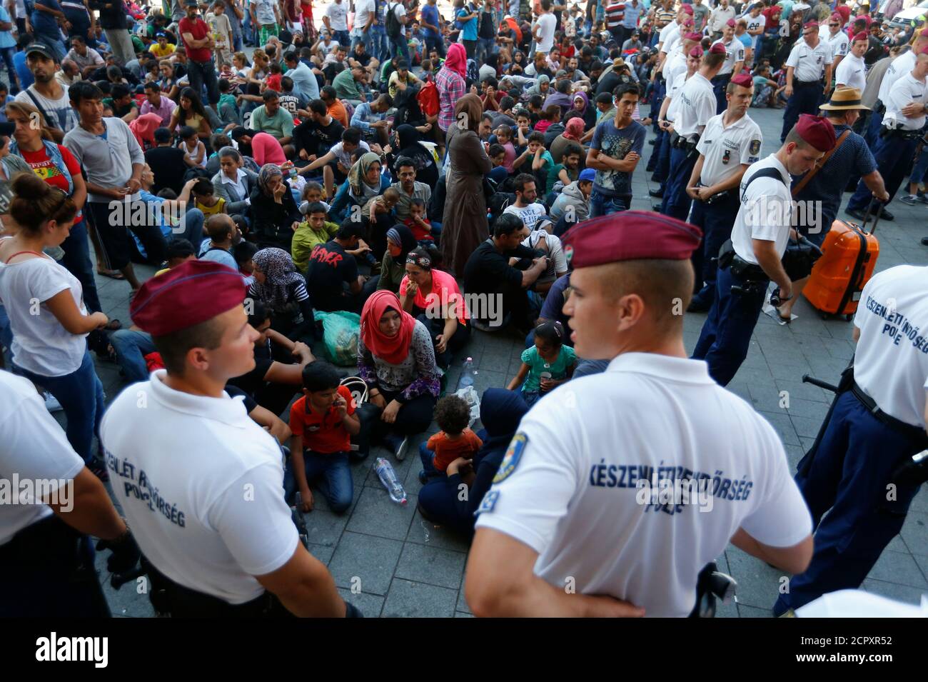 Hungarian police officers watch migrants outside the main Eastern Railway station in Budapest, Hungary, September 1, 2015. Hungary closed Budapest's main Eastern Railway station on Tuesday morning with no trains departing or arriving until further notice, a spokesman for state railway company MAV said. There are hundreds of migrants waiting at the station. People have been told to leave the station and police have lined up at the main entrance, national news agency MTI reported. REUTERS/Laszlo Balogh Stock Photo