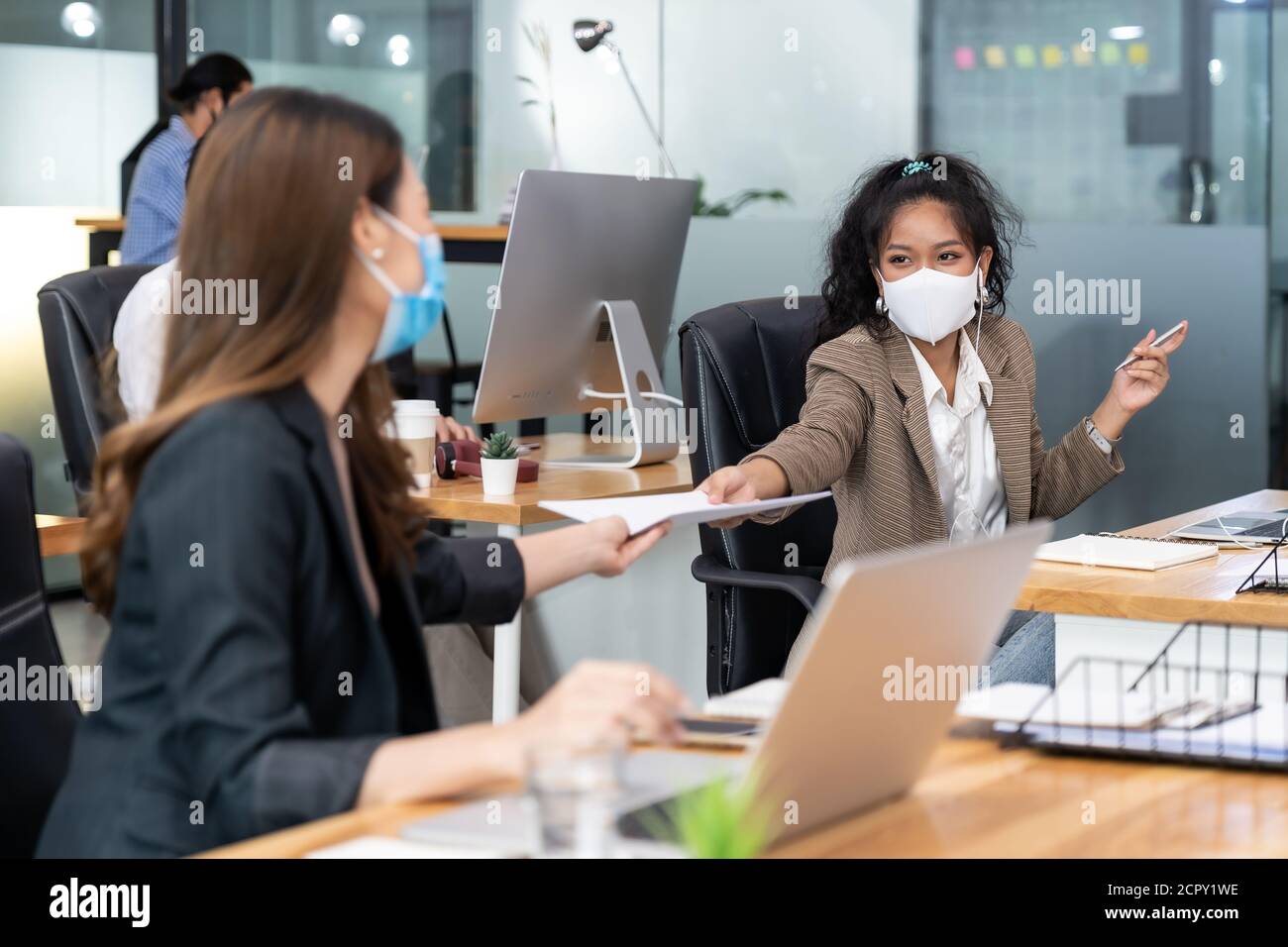 Group of interracial business worker team wear protective face mask in new normal office with social distance practice with hand sanitiser alcohol gel Stock Photo