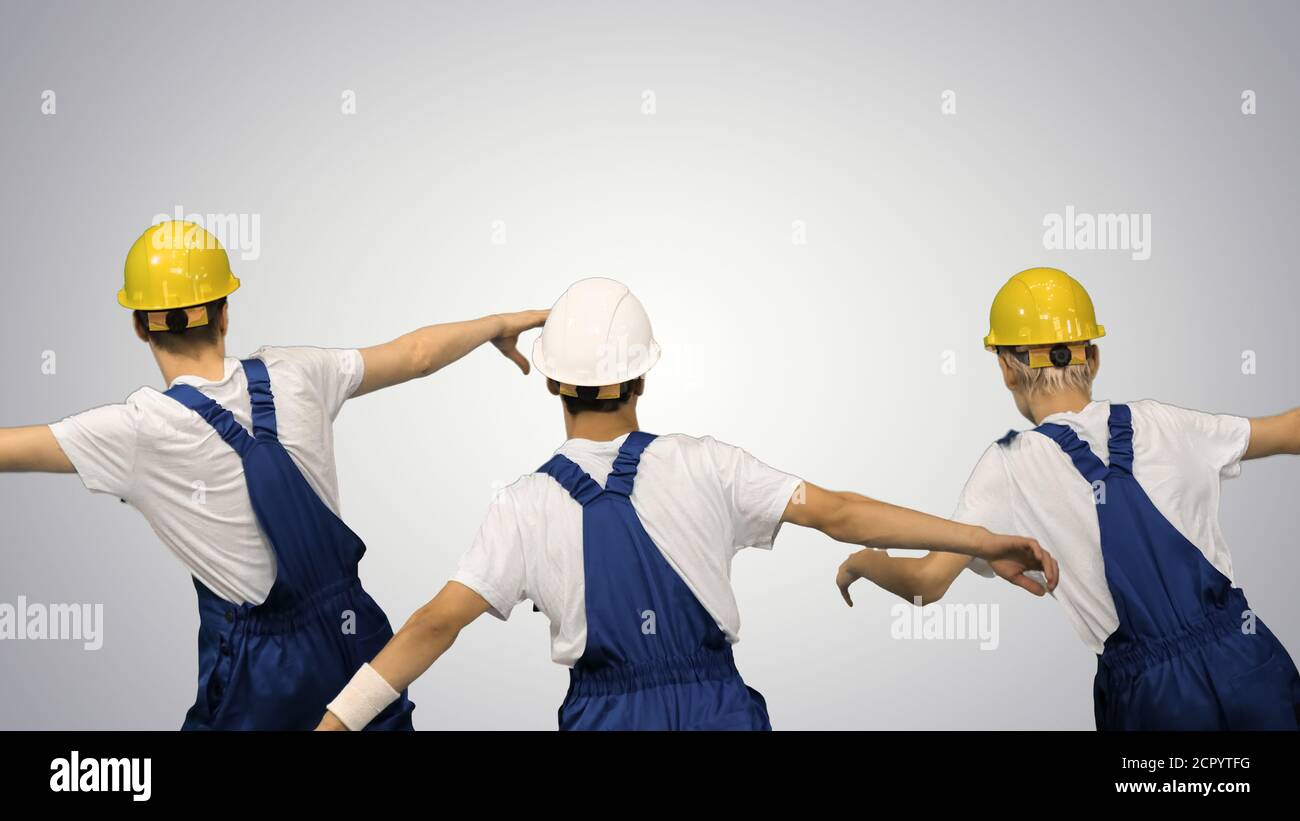 Three male construction workers in hard hats synch dancing with Stock Photo
